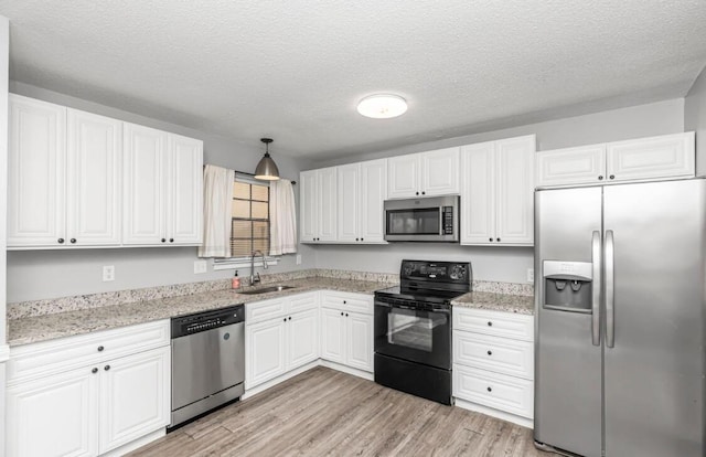 kitchen featuring white cabinets, sink, hanging light fixtures, light hardwood / wood-style floors, and stainless steel appliances