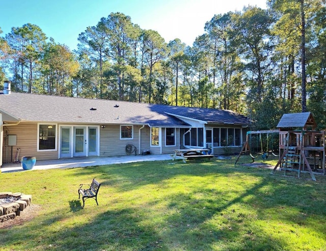 rear view of property featuring a sunroom, a patio area, a playground, and a yard