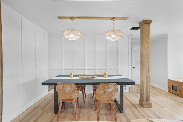 dining space with light wood-type flooring, ornamental molding, and ornate columns