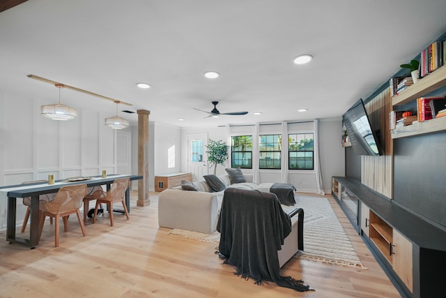 living room featuring ceiling fan, light wood-type flooring, and decorative columns