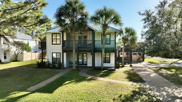 view of front facade with ceiling fan, a balcony, a front lawn, and french doors