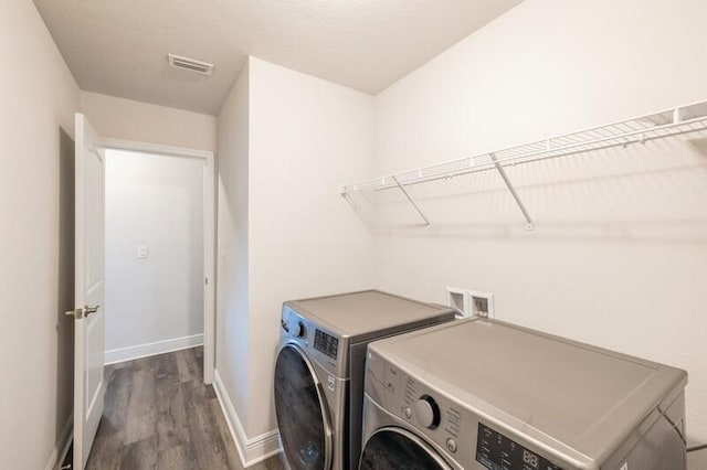 washroom with dark hardwood / wood-style flooring and washing machine and clothes dryer