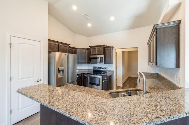 kitchen with kitchen peninsula, stainless steel appliances, light stone counters, and sink