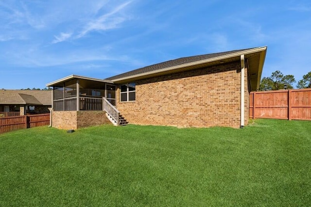 rear view of house with a lawn and a sunroom