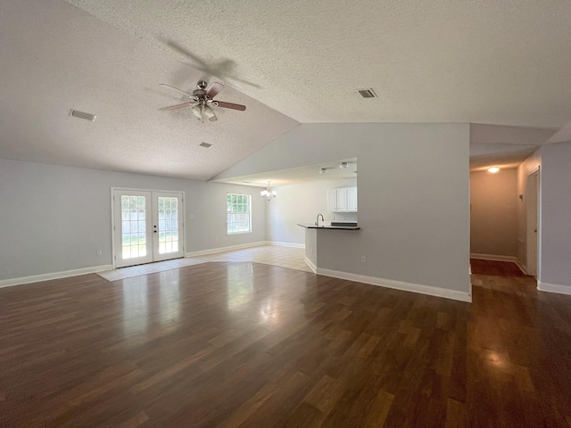 unfurnished living room with lofted ceiling, dark wood-type flooring, and a textured ceiling