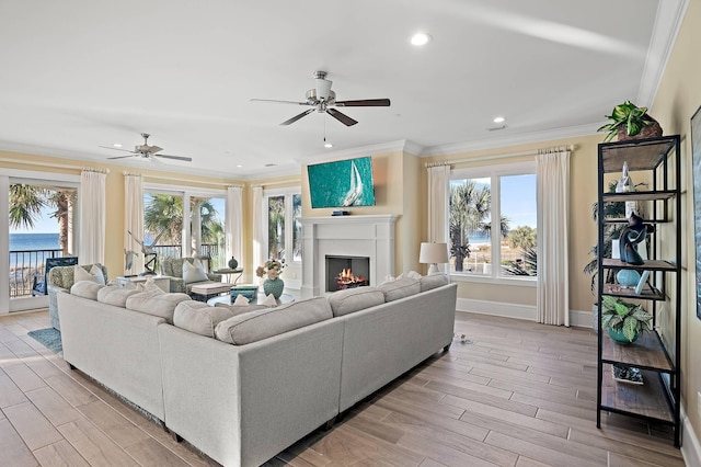 living room with light wood-type flooring, ceiling fan, a wealth of natural light, and a water view