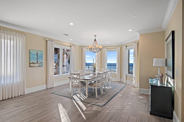 dining area featuring a water view, a wealth of natural light, crown molding, and light hardwood / wood-style floors