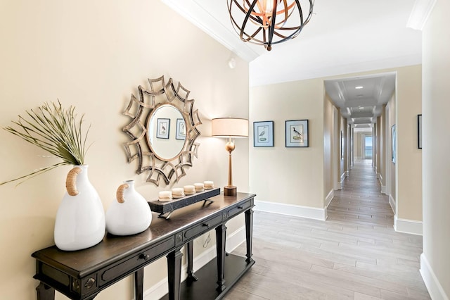 hallway featuring light wood-type flooring, an inviting chandelier, and crown molding