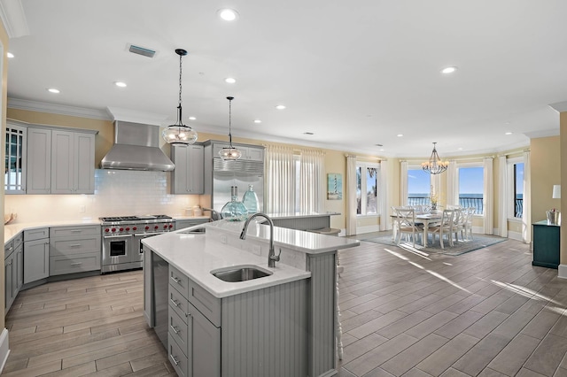 kitchen featuring sink, wall chimney range hood, gray cabinets, and high end appliances