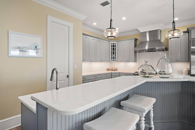 kitchen featuring decorative light fixtures, decorative backsplash, wall chimney exhaust hood, and gray cabinetry