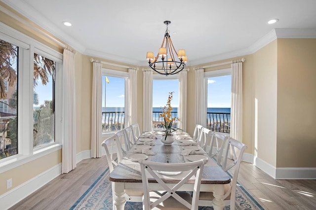 dining room featuring a water view, plenty of natural light, an inviting chandelier, and ornamental molding