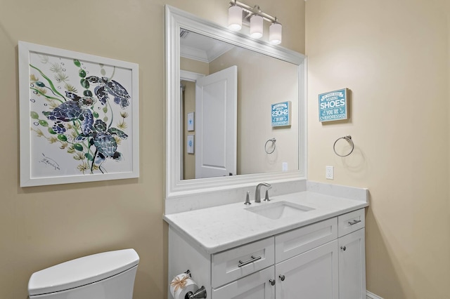 bathroom with toilet, vanity, and ornamental molding