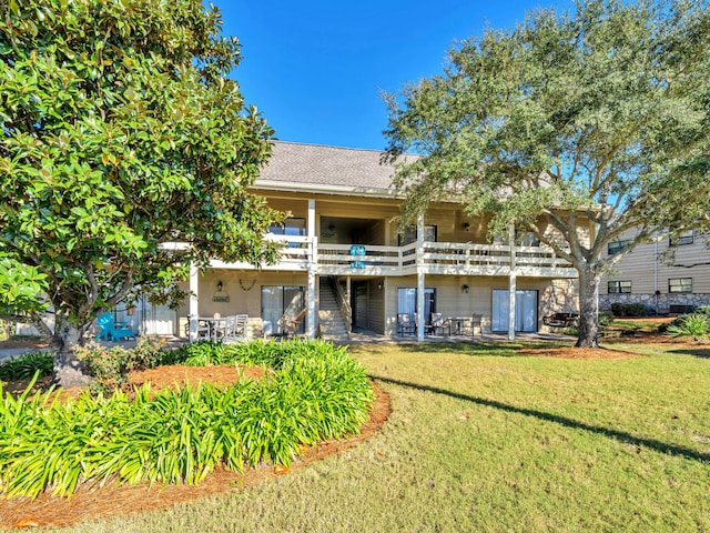 back of house with a yard and a balcony