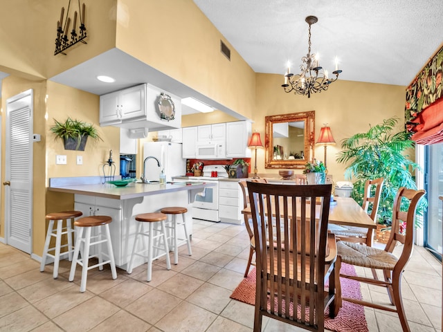 kitchen with white cabinets, a notable chandelier, white appliances, a kitchen bar, and light tile patterned floors