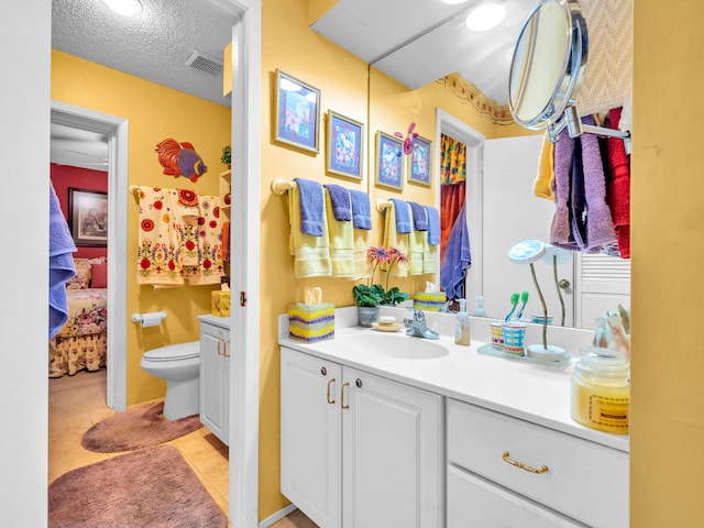 bathroom with tile patterned flooring, vanity, toilet, and a textured ceiling