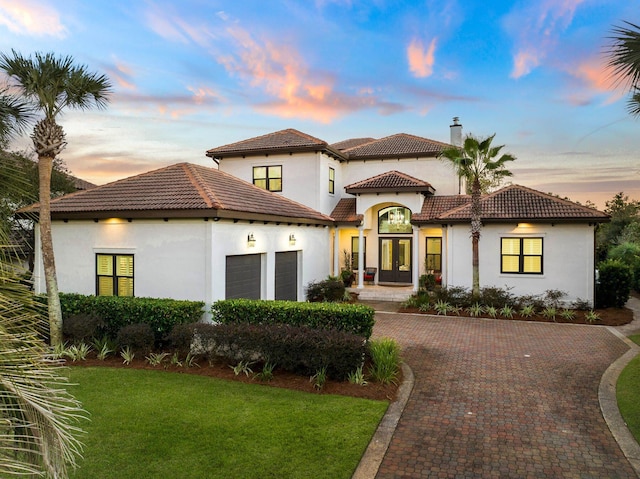 mediterranean / spanish house with a lawn, french doors, and a garage