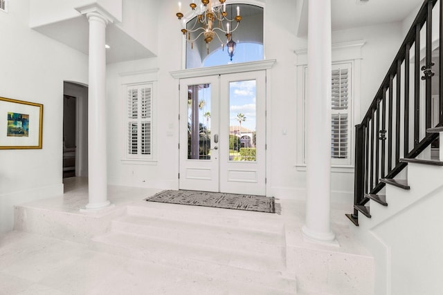 entryway with french doors, a towering ceiling, and an inviting chandelier