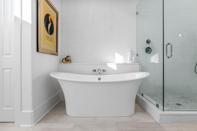 bathroom featuring tile patterned floors, separate shower and tub, and tile walls