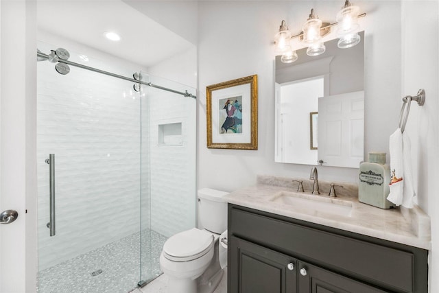 bathroom featuring vanity, a shower with shower door, and toilet