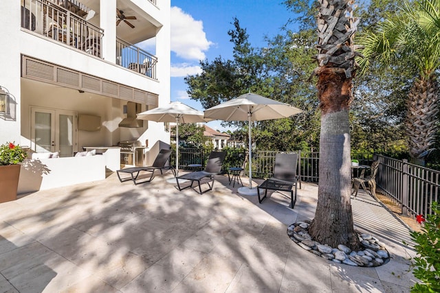 view of patio / terrace featuring grilling area, ceiling fan, a balcony, and an outdoor kitchen