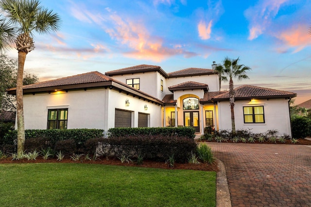 mediterranean / spanish home featuring a yard and a garage