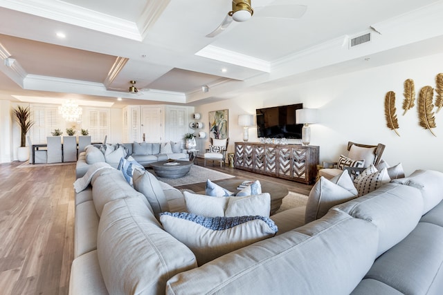 living room with hardwood / wood-style flooring, ceiling fan, ornamental molding, and a tray ceiling