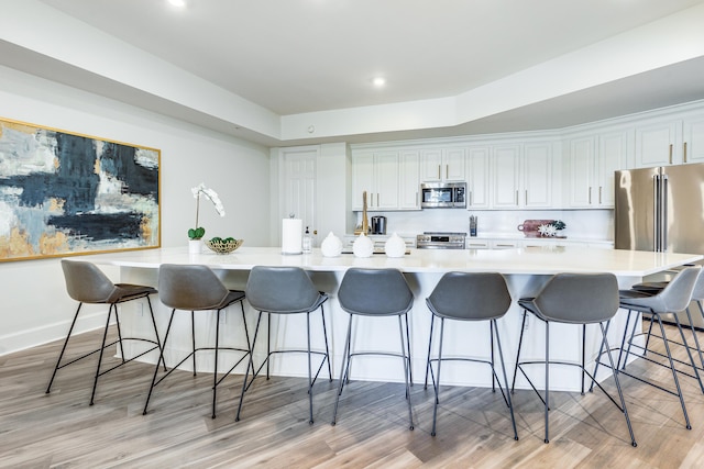 kitchen with white cabinetry, stainless steel appliances, and a breakfast bar area