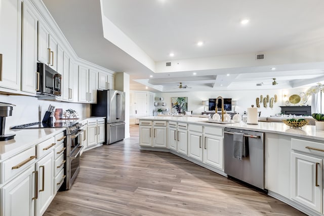 kitchen with beam ceiling, stainless steel appliances, white cabinetry, and light hardwood / wood-style flooring