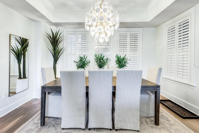 dining space featuring hardwood / wood-style floors, a tray ceiling, ornamental molding, and a notable chandelier