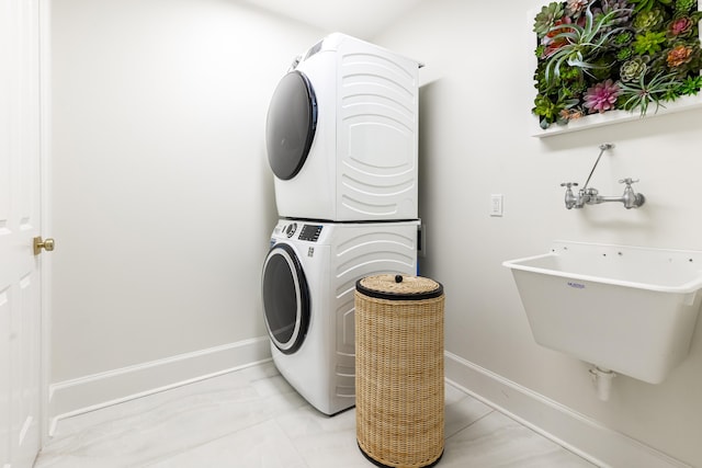 laundry area with light tile patterned floors, stacked washer / drying machine, and sink