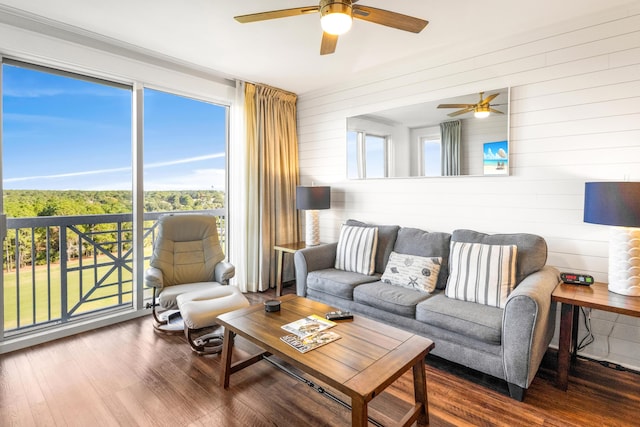 living room featuring a wealth of natural light, wooden walls, ceiling fan, and hardwood / wood-style flooring