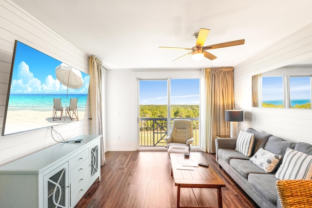 living room with plenty of natural light, dark hardwood / wood-style floors, a water view, and ceiling fan