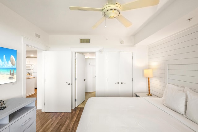 bedroom with dark hardwood / wood-style flooring, a closet, ceiling fan, and white refrigerator