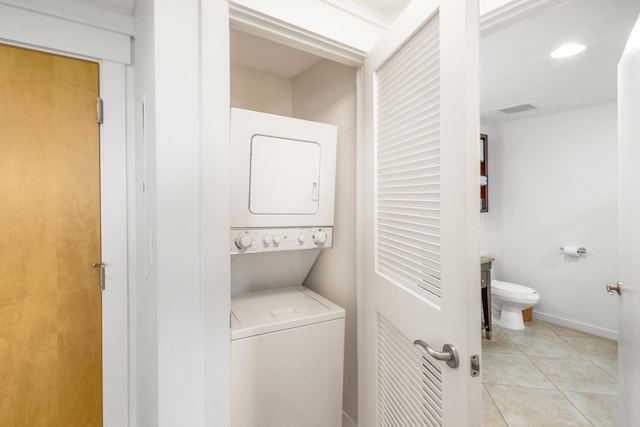 laundry room featuring light tile patterned floors and stacked washer / drying machine