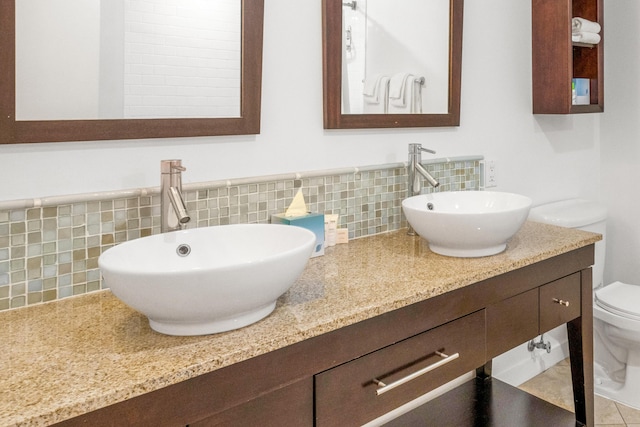 bathroom with tile patterned flooring, vanity, toilet, and tasteful backsplash