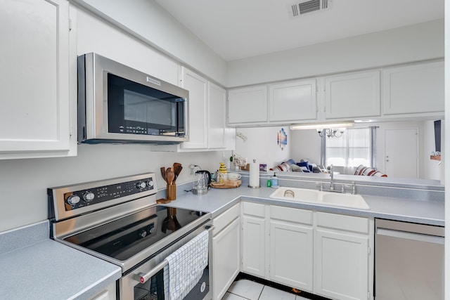 kitchen with stainless steel appliances, sink, light tile patterned floors, a notable chandelier, and white cabinets