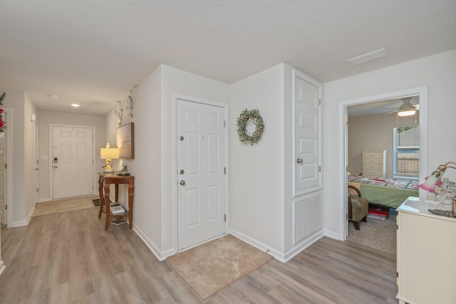 foyer entrance with a textured ceiling, light hardwood / wood-style flooring, and ceiling fan