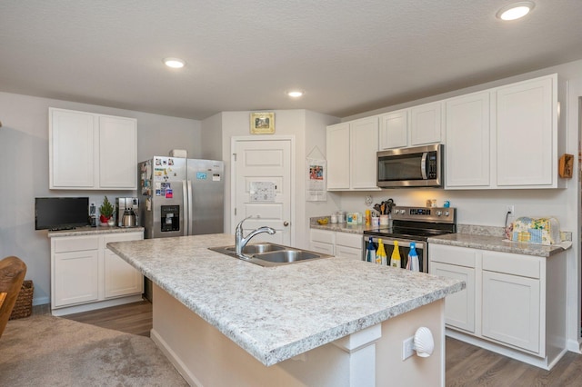 kitchen with white cabinets, sink, stainless steel appliances, and a kitchen island with sink