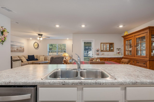 kitchen with dishwasher, a center island with sink, ceiling fan, and sink