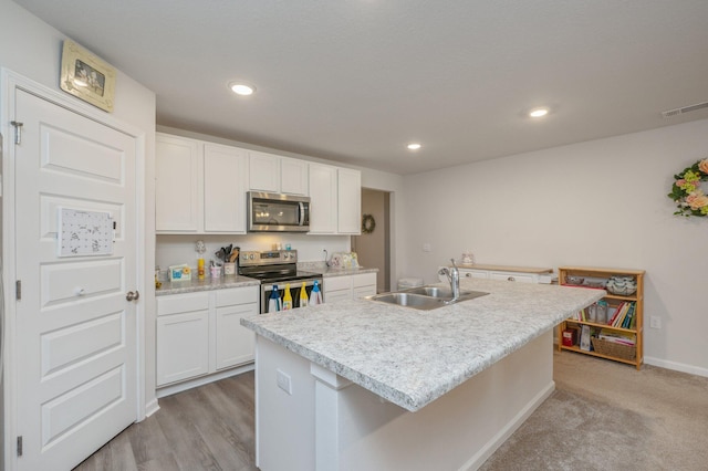 kitchen featuring white cabinets, stainless steel appliances, a kitchen island with sink, and sink