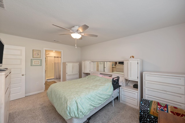 carpeted bedroom with a textured ceiling, ensuite bath, and ceiling fan