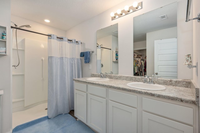 bathroom with a textured ceiling, vanity, and walk in shower