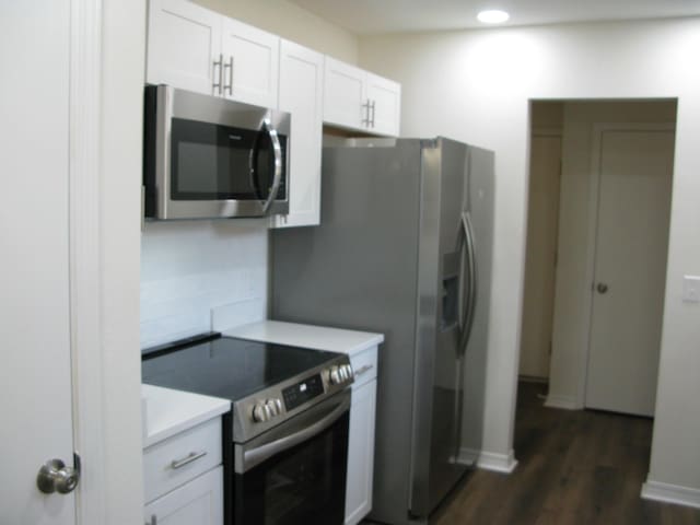 kitchen featuring white cabinetry, dark hardwood / wood-style flooring, and appliances with stainless steel finishes