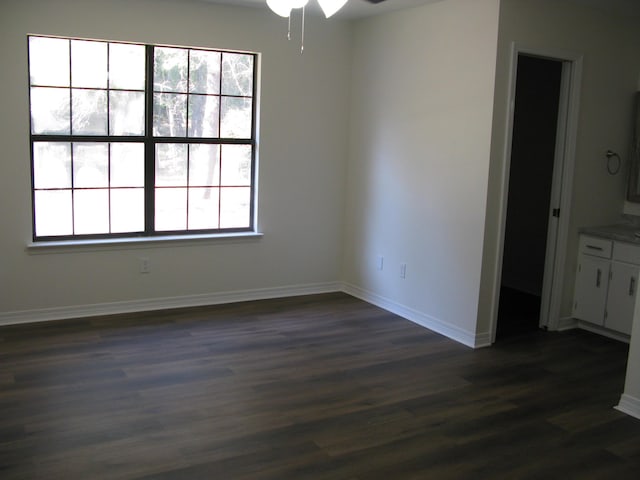 empty room with ceiling fan and dark wood-type flooring