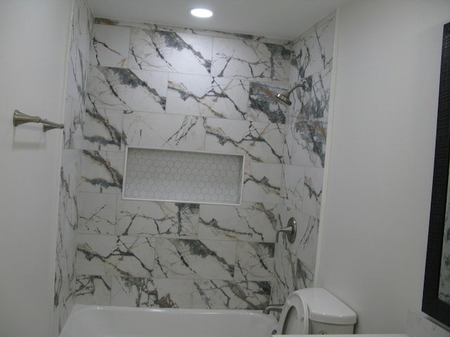 bathroom with tiled shower / bath combo and toilet