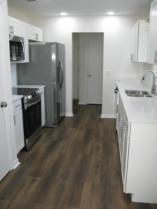 kitchen with white cabinets, sink, appliances with stainless steel finishes, and dark wood-type flooring