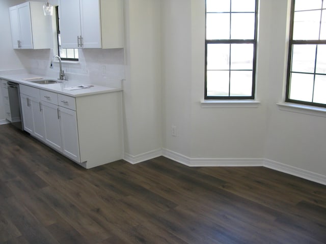 kitchen with sink, dark hardwood / wood-style flooring, stainless steel dishwasher, decorative backsplash, and white cabinets