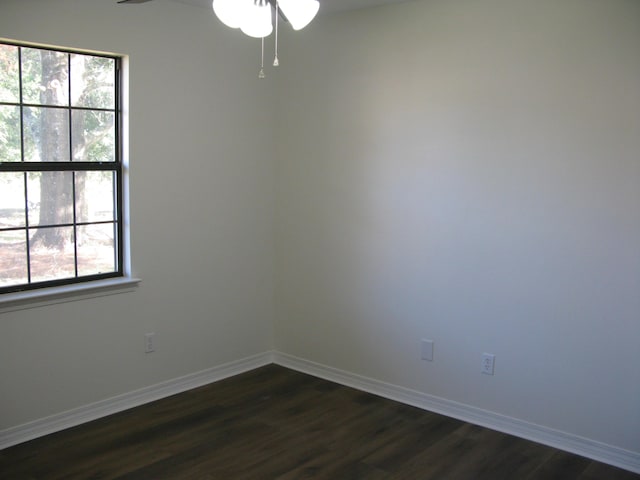 empty room with a wealth of natural light, dark wood-type flooring, and ceiling fan