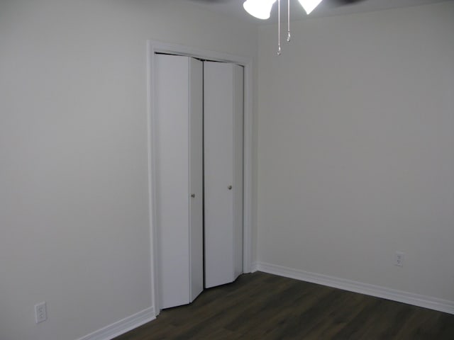 unfurnished bedroom with dark hardwood / wood-style flooring and a closet