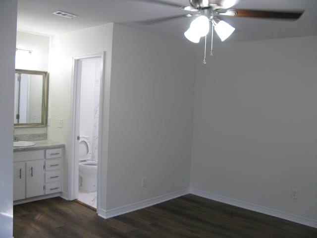 interior space with ensuite bathroom, ceiling fan, sink, and dark wood-type flooring